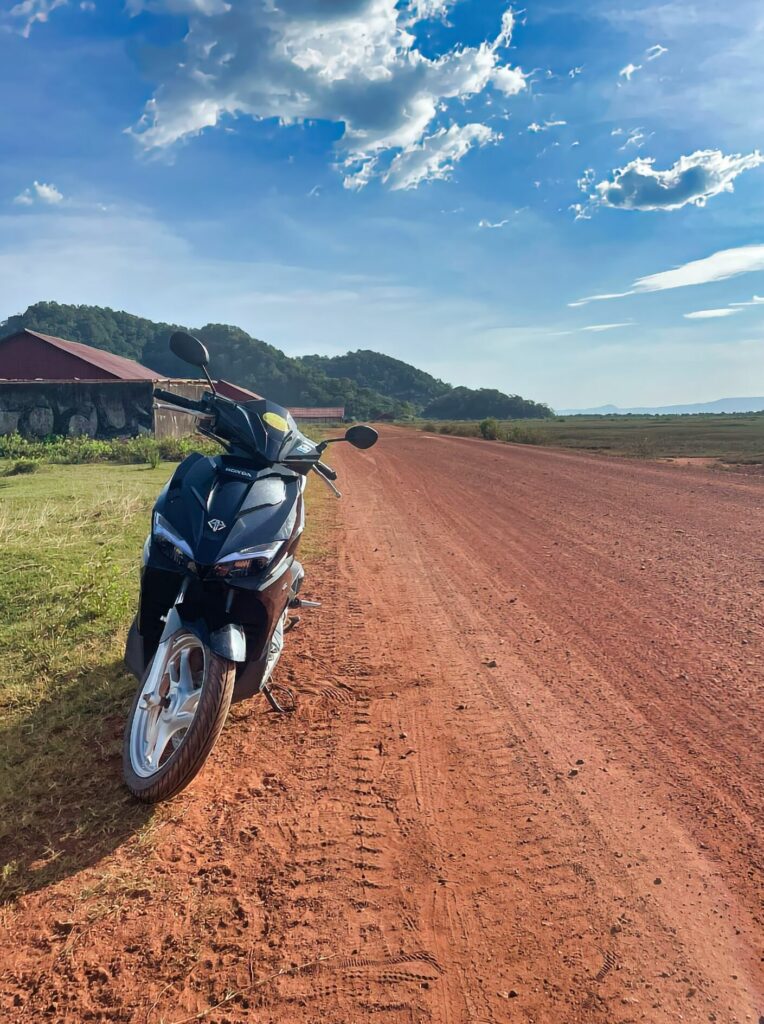 Scooter garé au bord d'une route de terre dans la région de Kampot, au Cambodge.