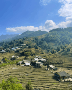 Vue sur une partie du village Hmongs entourée de rizières et de végétation.